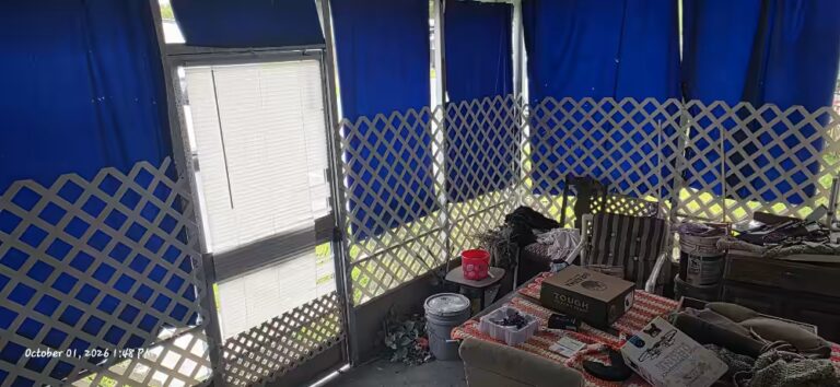 Cluttered enclosed porch with blue tarps and white lattice; timestamp reads October 01, 2026 1:45 PM.